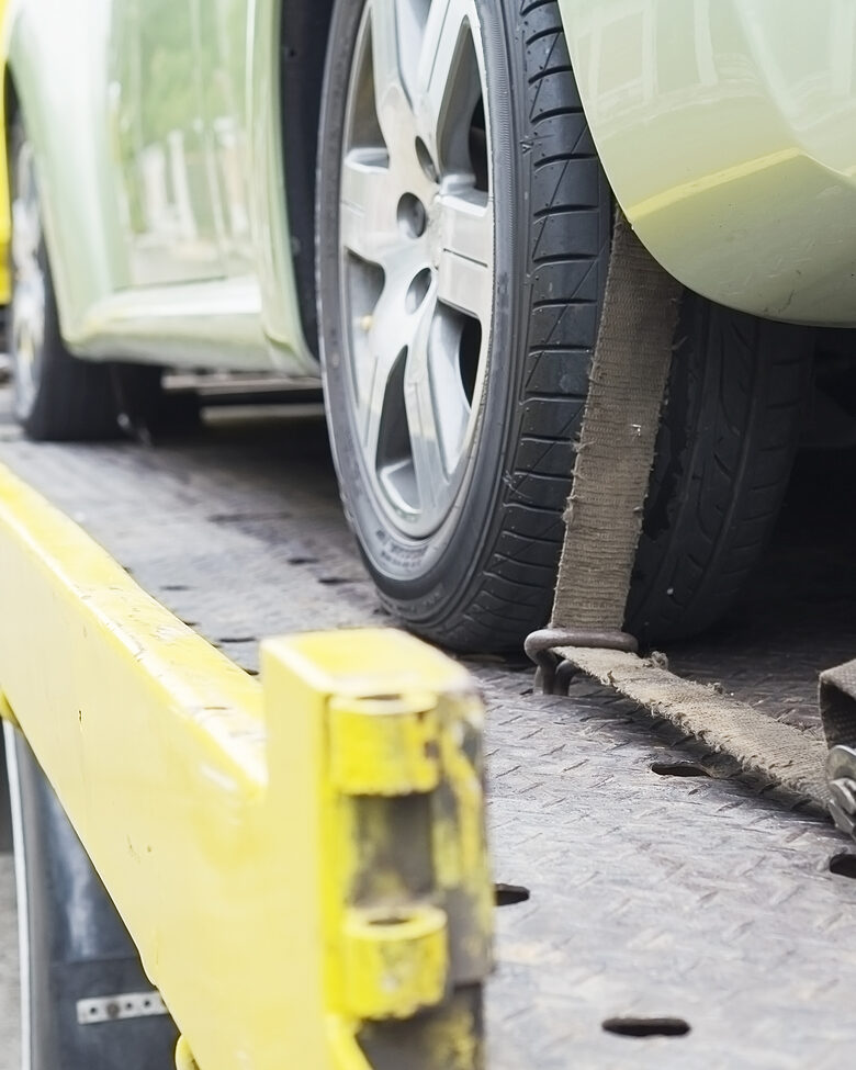Samochód wjechany na lawetę, koło spięte pasem transportowym